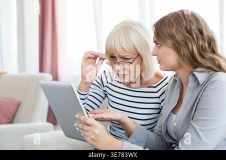Donna che insegna a una donna anziana di usare un tablet Foto Stock