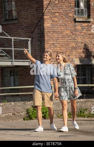 Giovani coppie che esplorano insieme la città indicando attrazioni turistiche nelle giornate di sole Foto Stock