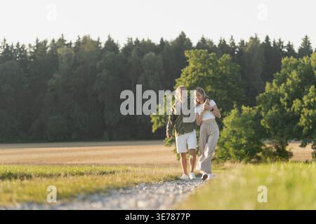 Coppia felice che cammina attraverso il paesaggio aperto godendosi la luce estiva Foto Stock