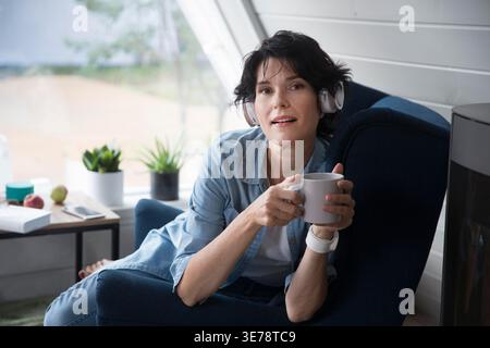 Correzione audio. concetto senza stress. stile di vita sano. salute emotiva. riposati dai gadget. una donna di mezza età con le cuffie ascolta la musica a casa Foto Stock