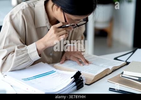 Donna d'affari anziana che afferra gli occhiali per guardare i documenti controlla le informazioni meticolosamente e diligentemente nel tuo lavoro. Foto Stock