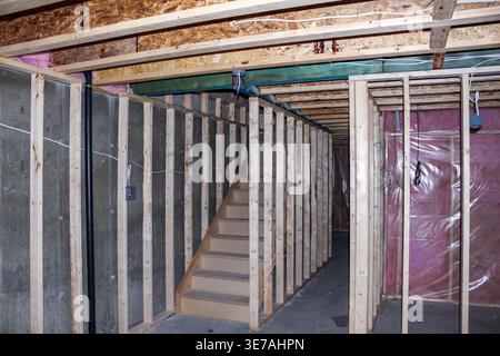 Cantiere interrato non finito che presenta intelaiature in legno, pareti in cemento esposte e una scala che porta al livello superiore dell'edificio Foto Stock