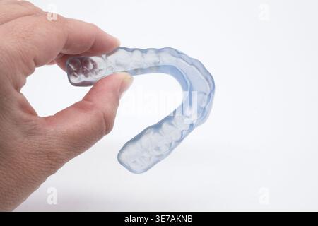 Medico che tiene in mano una protezione notturna trasparente su misura per proteggere i denti dalla smerigliatura Foto Stock