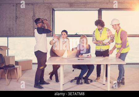 Uomo nero che usa occhiali VR mentre incontra uomini d'affari in cantiere Foto Stock