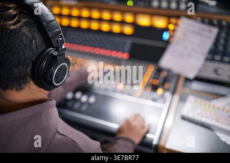 Donna da corsa mista che indossa le cuffie per registrare musica su una postazione audio Foto Stock