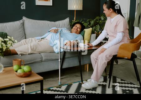 Donna nera anziana e giovane infermiera ispanica sorridente a ciascuno come risultato di una buona pressione sanguigna risultato Foto Stock