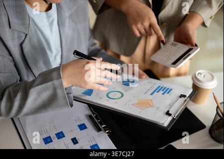 Donna d'affari che indossa un cappotto grigio che controlla il rapporto con il suo collega in ufficio Foto Stock