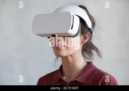 Donna da corsa mista che indossa un visore VR in piedi nel salotto di casa Foto Stock