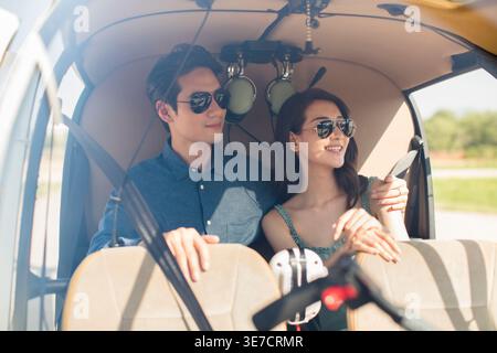 Coppia cinese sorridente con occhiali da sole in elicottero Foto Stock