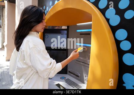 Donna giapponese in piedi per strada e ritirare soldi dal bancomat durante il giorno Foto Stock