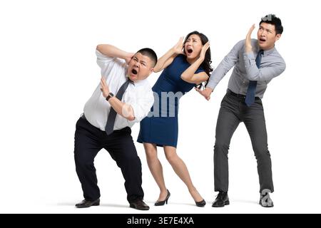 Spaventava gli uomini d'affari cinesi che si appoggiavano all'indietro e coprivano le orecchie mentre erano in piedi su sfondo bianco in studio Foto Stock