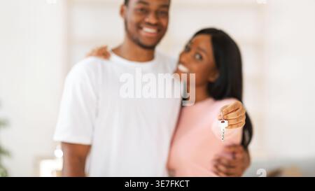 Coppia nera sorridente che mostra la chiave mentre sta insieme a casa Foto Stock