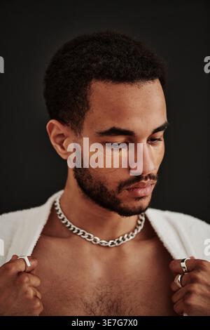 Serious Mixed Race Bearded man con patch per gli occhi che fissano la camicia su sfondo nero in studio Foto Stock