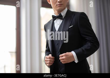 Uomo cinese con le mani sul completo in piedi a casa Foto Stock
