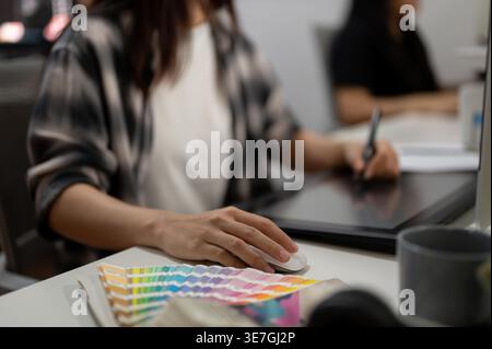Donna asiatica che lavora al computer seduta al tavolo in ufficio Foto Stock