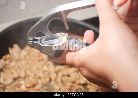 Cucinare con una pressa per aglio in un ambiente di cucina casalingo Foto Stock