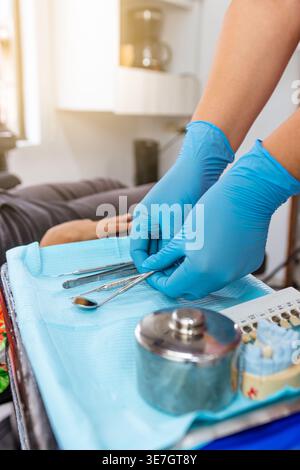 Mani di dentista donna razza mista che organizza strumenti dentali su vassoio in clinica Foto Stock