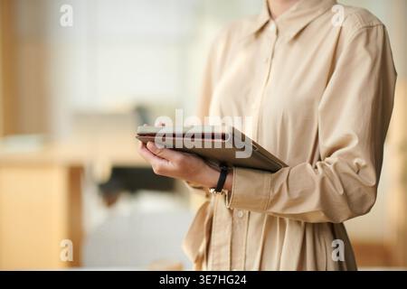 Immagine ritagliata di una donna d'affari asiatica che tiene un tablet in piedi in ufficio Foto Stock