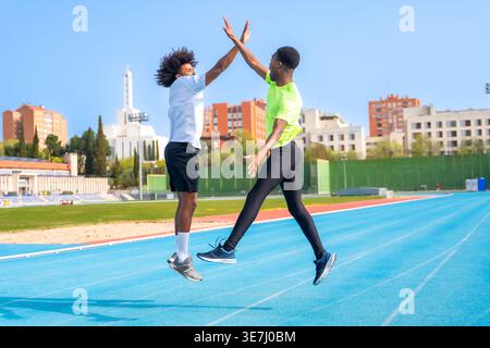 Corridori maschi neri che si regalano cinque salti in pista nelle giornate di sole Foto Stock