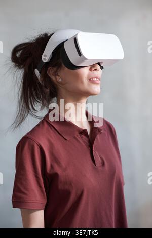 Donna da corsa mista che indossa un visore VR in piedi nel salotto di casa Foto Stock