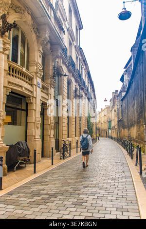 A Bordeaux, Francia, il 08.30.25, il turista cammina lungo Rue Teulère, una tradizionale strada acciottolata con architettura storica Foto Stock