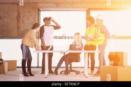 Uomo nero che usa occhiali VR mentre incontra uomini d'affari in cantiere Foto Stock
