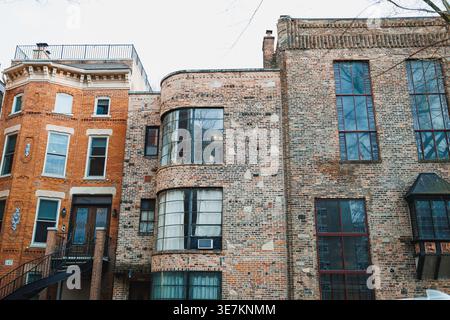 Due edifici in mattoni si trovano in un'area della citta'. Un edificio e' arrotondato con grandi finestre, mentre l'altro ha un design piatto e molte finestre. La sk Foto Stock