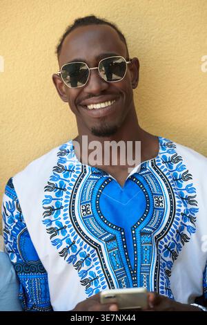 L'uomo africano nero del Sudan nativo che usa lo smart phone e indossa i vestiti tradizionali Foto Stock