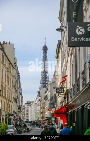 PARIGI, FRANCIA — 11 APRILE 2026: Vista della Torre Eiffel dalla Rue Saint-Dominique con pedoni, edifici e cartelli per negozi, tra cui Iser Foto Stock