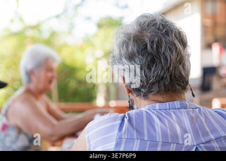 Donne anziane ispaniche sedute sul portico durante il giorno Foto Stock