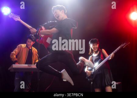 Gruppo di musicisti cinesi che si esibiscono sul palco con luci blu e rosse all'interno Foto Stock