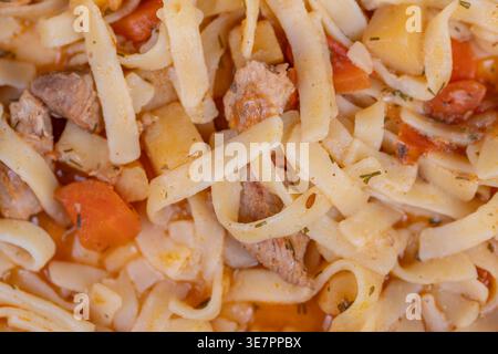 Struttura in stile lagman fatta in casa per uso commerciale. Focalizzazione su fili di spaghetti, mix di carne e verdure a cubetti, colori caldi e vivaci, ideale per i pacchetti Foto Stock