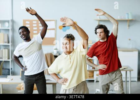 Gruppo di uomini d'affari che svolgono attività di stretching mentre si trovano in ufficio Foto Stock