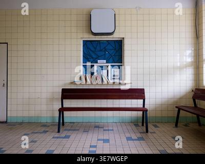 Vista simmetrica di una sala d'attesa della stazione ferroviaria con una panca di legno e libri su un davanzale della finestra nella Repubblica Ceca Foto Stock