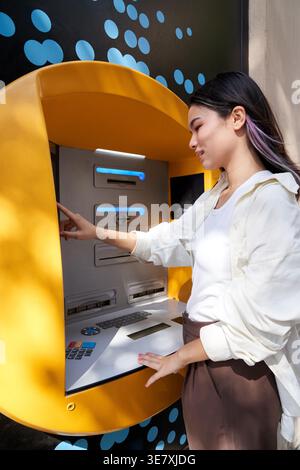 Donna giapponese in piedi per strada e ritirare soldi dal bancomat durante il giorno Foto Stock