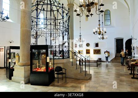 I visitatori esplorano l'interno della sinagoga di Cracovia, Polonia. Vedono manufatti e opere d'arte in un contesto culturale. Foto Stock