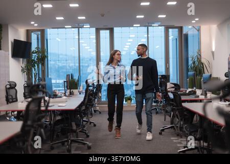 Uomini neri e donne caucasiche che parlano mentre camminano in ufficio Foto Stock