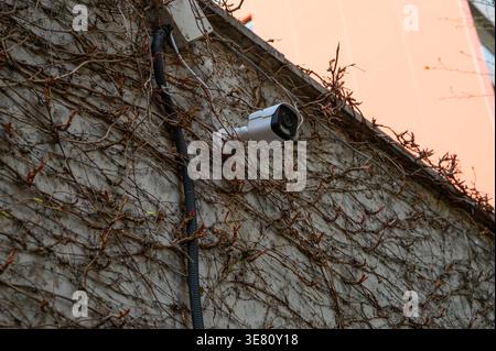 Immagine ad alta risoluzione di una telecamera di sorveglianza IP montata sulla parete esterna di un edificio. Il dispositivo supporta la tecnologia PoE Power over Ethernet, Foto Stock
