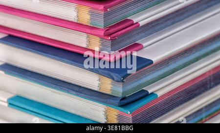 Una pila di libri colorati con copertine rosa e blu vivaci, che evidenziano la trama dei bordi della carta. Primo piano. Foto Stock