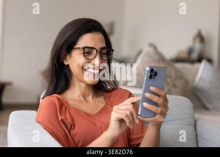 Donna sorridente che usa lo smartphone a casa Foto Stock