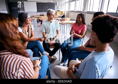Studenti e insegnanti che hanno una discussione di gruppo in cerchio Foto Stock