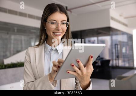 Una giovane donna d'affari lavora con fiducia nello spazio di lavoro con un dispositivo tablet Foto Stock