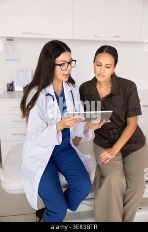 Il medico conduce la consultazione del paziente, mostrando i risultati dei test su tablet digitale Foto Stock