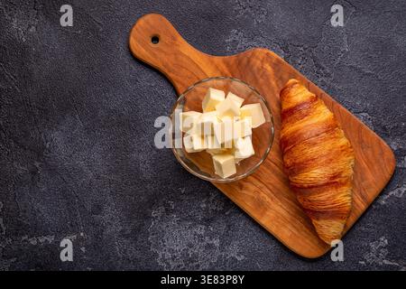 Croissant francese. Croissant appena sfornati con burro su fondo di pietra scura. Foto Stock