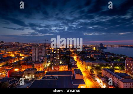 Dnipro, Ucraina, una splendida vista aerea panoramica della vibrante città al crepuscolo, che mostra il paesaggio illuminato della città, il fiume Dnieper e i ponti un Foto Stock
