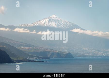 Vista panoramica del monte Teide che si innalza sopra la costa settentrionale di Tenerife, vista da El Pris con le acque dell'Atlantico, le scogliere e le morbide nuvole, che mostrano le Canarie Foto Stock