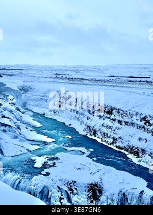 Splendido paesaggio invernale di un fiume ghiacciato di canyon con rocce innevate e cascate. Foto Stock