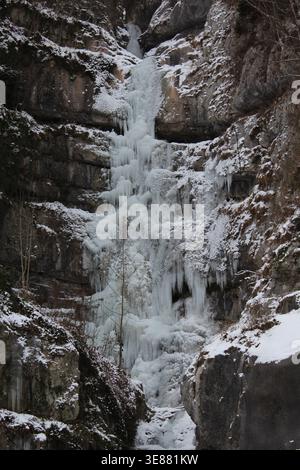 Una spettacolare cascata ghiacciata con enormi ghiaccioli aggrappati a una ripida parete rocciosa nella Valle Echerntal vicino a Hallstatt, Austria, durante l'inverno. Foto Stock