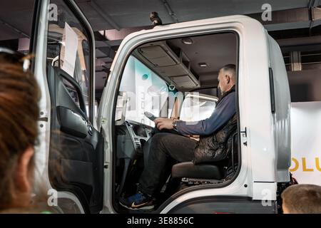 BELGRADO, SERBIA - 22 MARZO 2026: Uomo siede nella cabina di un veicolo elettrico Foton bianco, testando la posizione del conducente e la disposizione di un veicolo elettrico commerciale Foto Stock