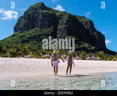 In una bella giornata a Mauritius, un paio di passeggiate lungo la tranquilla spiaggia, le dita si intrecciano. Le loro gioie risate riempiono l'aria mentre si godono le splendide vedute costiere di le Morne, Mauritius Foto Stock